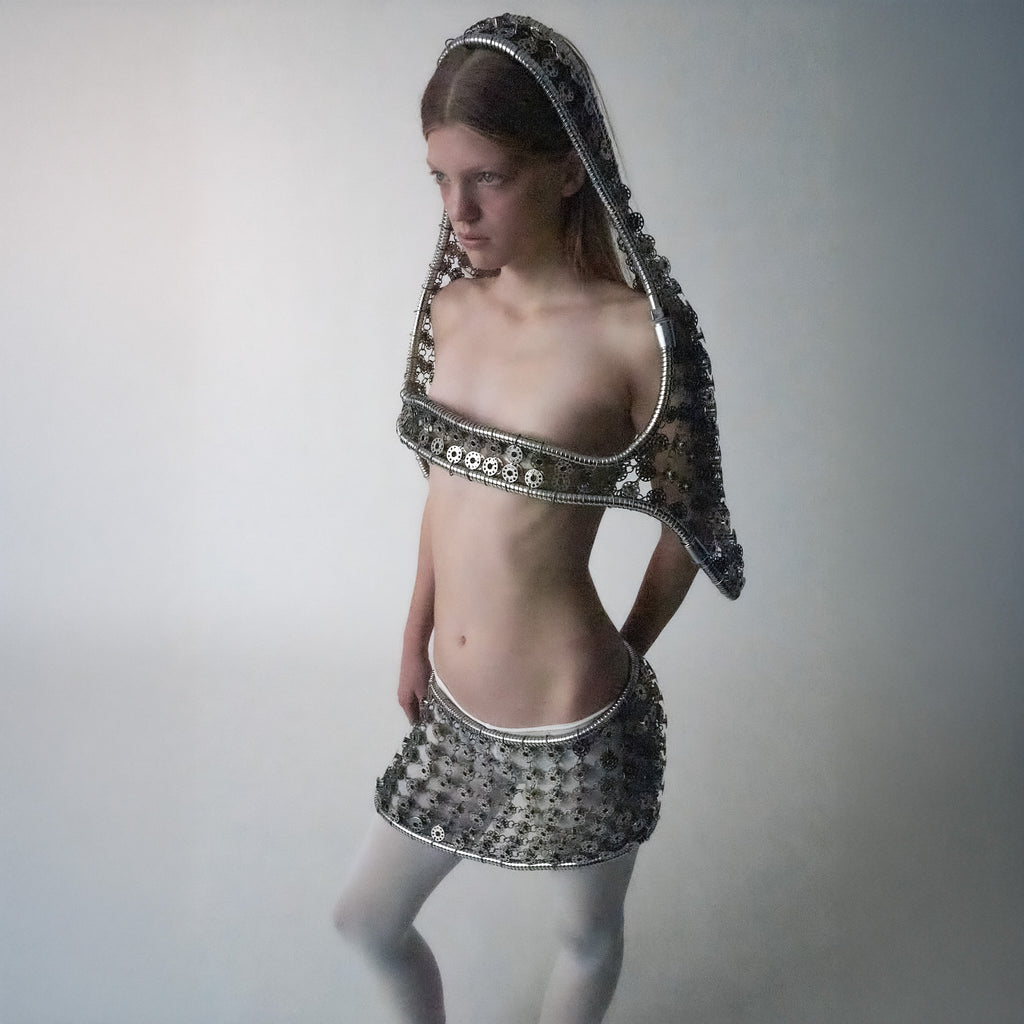 Person wearing a metallic bobbins-made outfit, featuring a mini skirt and a multi-wear top, on a light grey background.