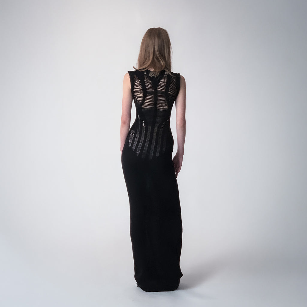 Long black knitted dress with floats details on a light grey background 