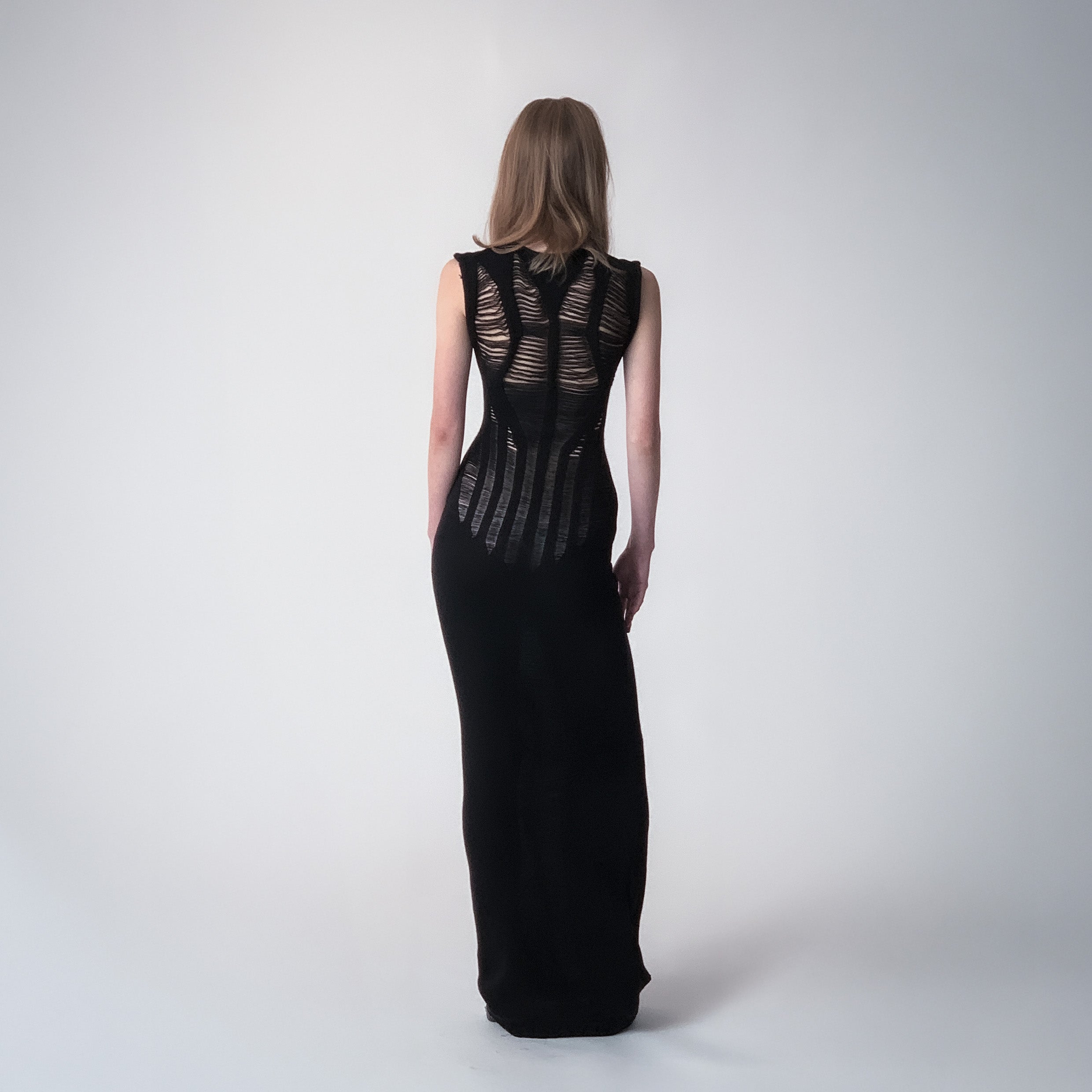 Long black knitted dress with floats details on a light grey background 