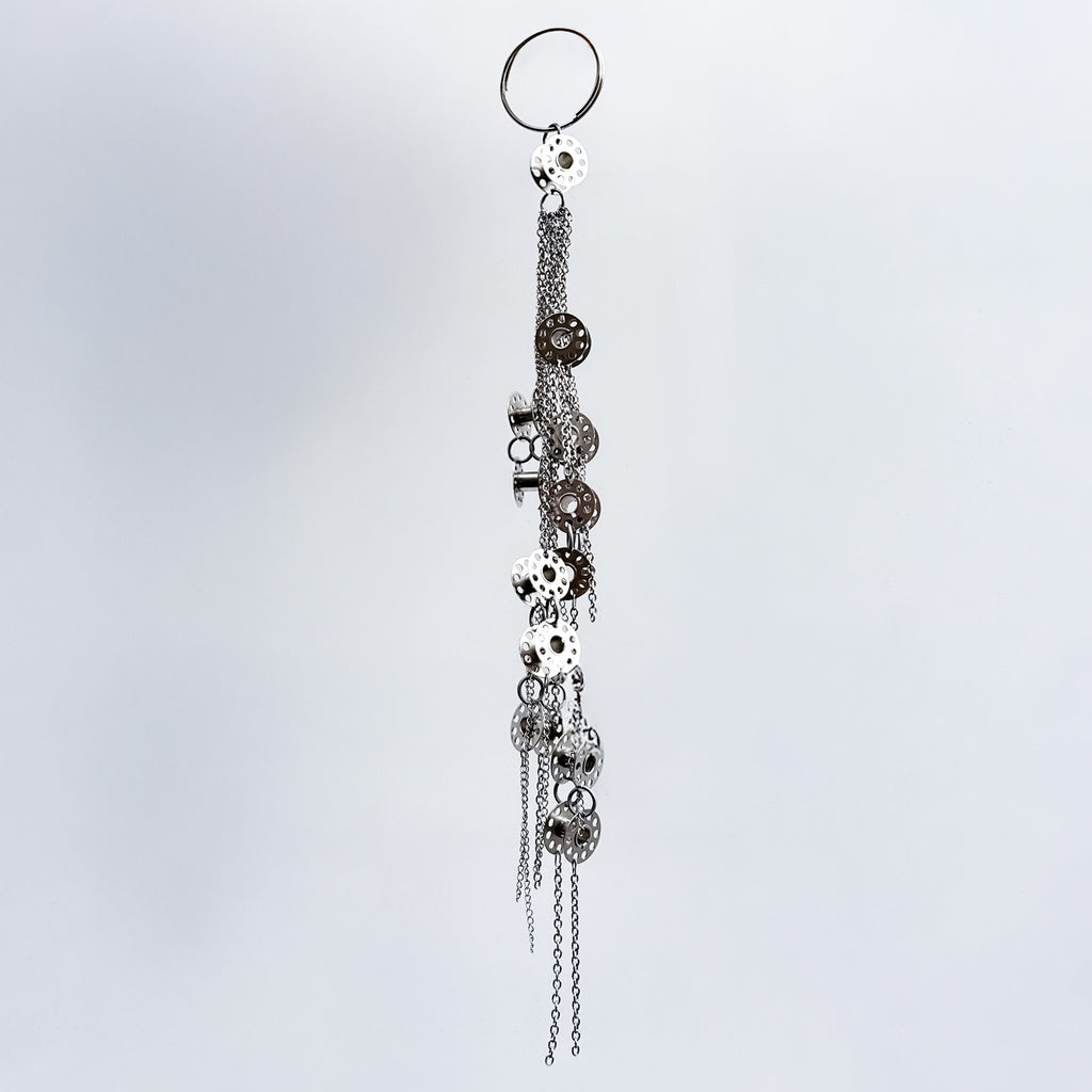 Decorative keychain with metal bobbins and chains on a light gray background