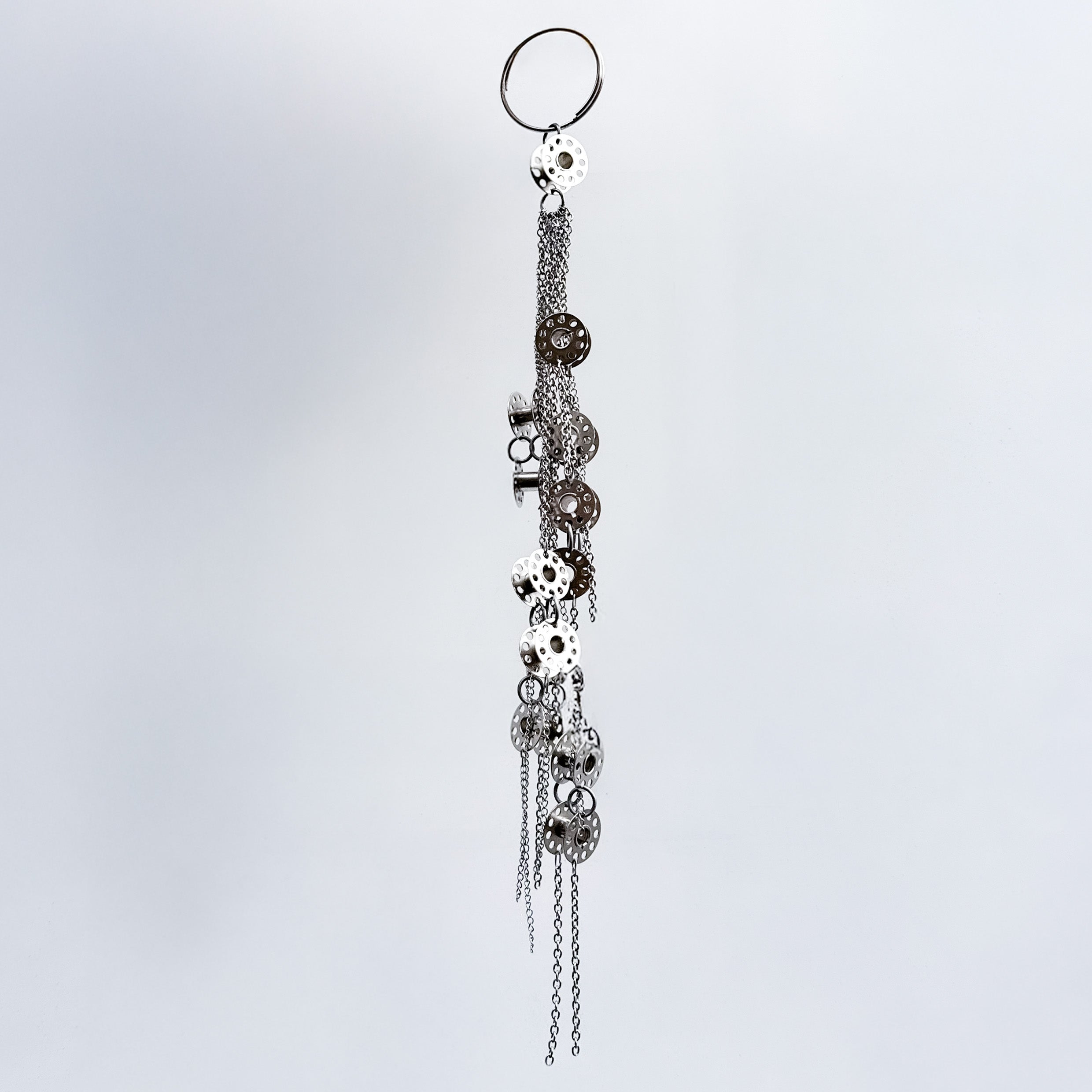 Decorative keychain with metal bobbins and chains on a light gray background