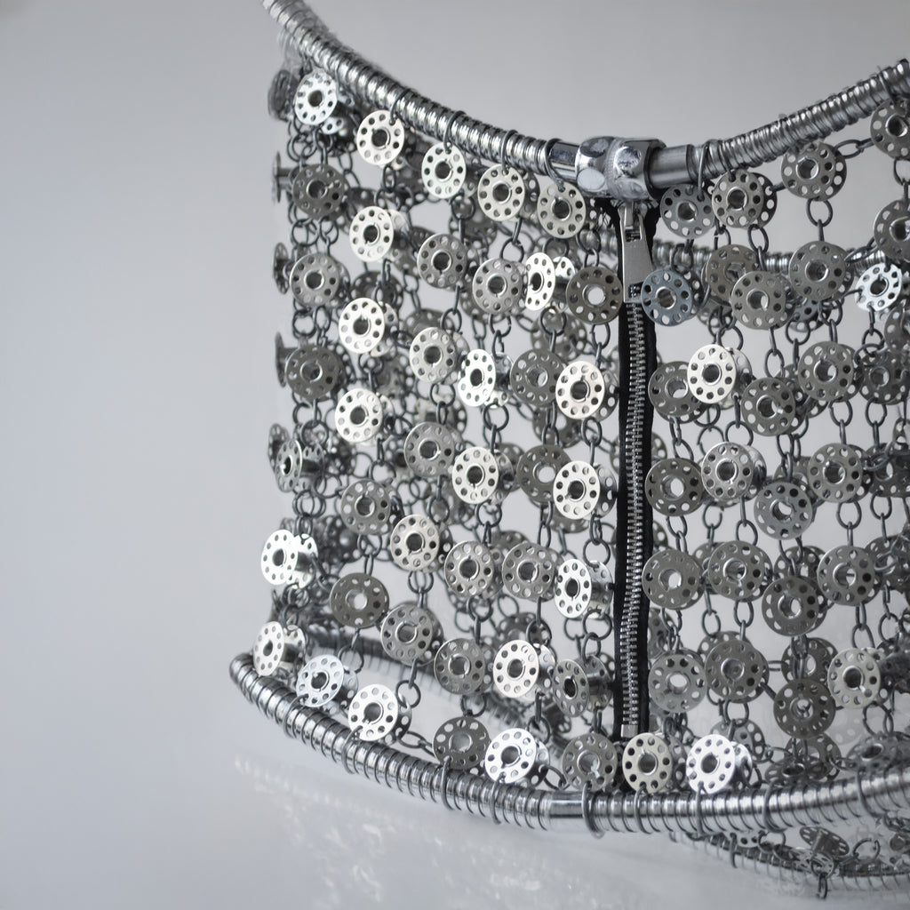 Metallic silver mini skirt out of bobbins on light gray background
