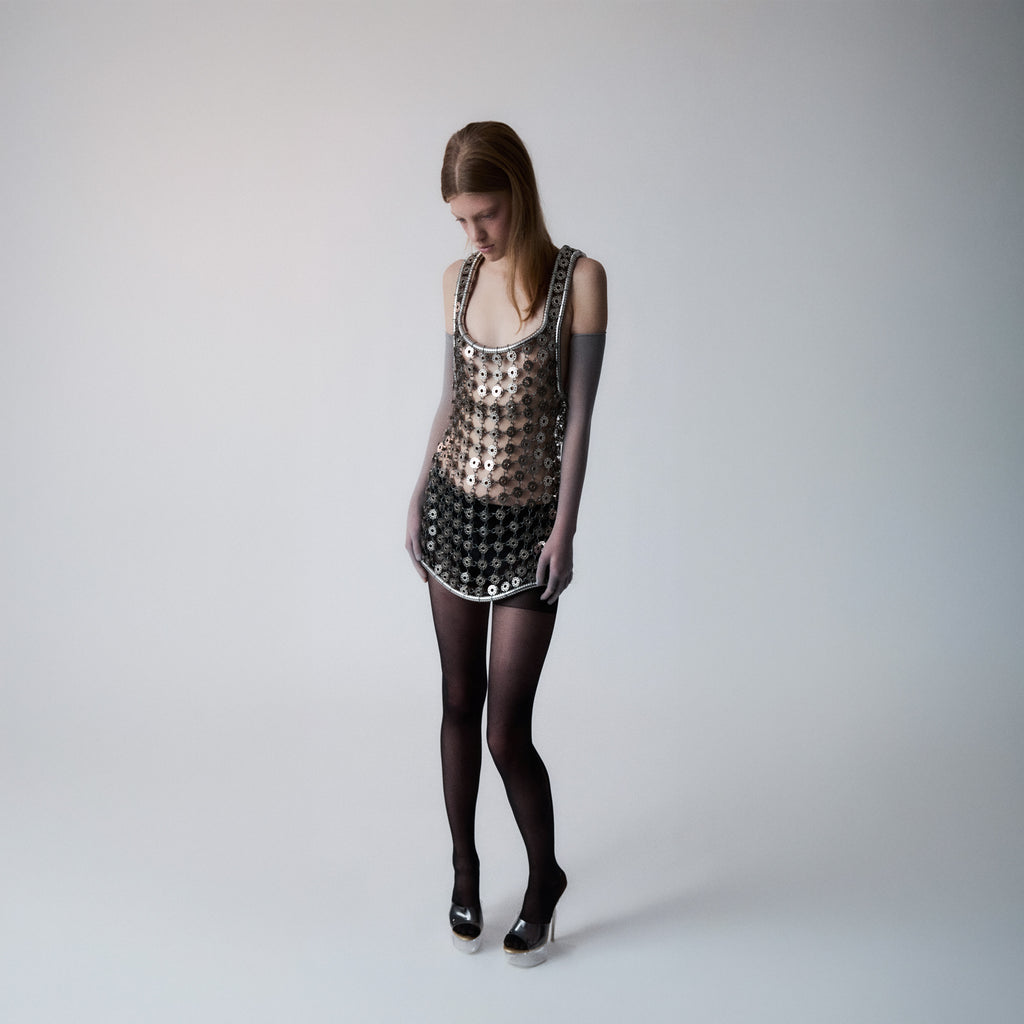 Person wearing a silver short dress out of bobbins on a light gray background 