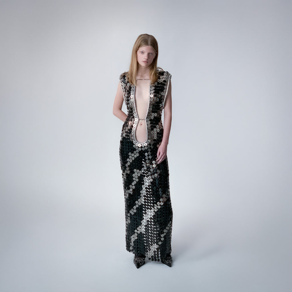 person wearing a long dress out of black and metallic  bobbins in a zebra pattern on a light gray background 